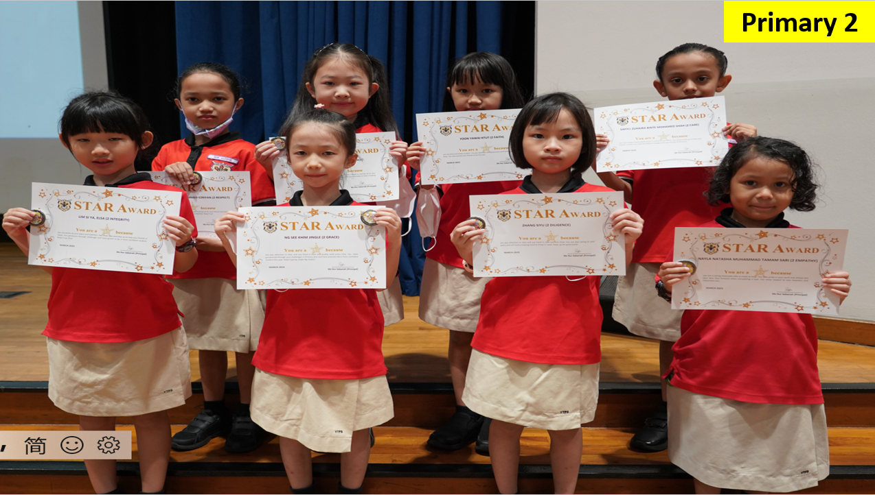 Eight Primary 2 students in red uniforms holding Star Award certificates while posing together on a stage.